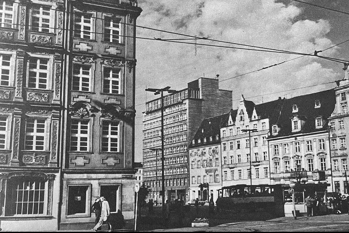 Going back to the 1970s, we can see the successful results of postwar rebuilding efforts. The facades are clean, pedestrians walk purposefully through the square, and power lines crisscross in the air. This photograph was taken by Joanna Drankowska, a photojournalist who often worked with her husband, Tadeusz Drankowski, to document architecture and everyday life in mid-century Wrocław. Source: Rutkiewicz, Ignacy. Wrocław: wczoraj i dziś. Warszawa: Interpress, 1979.